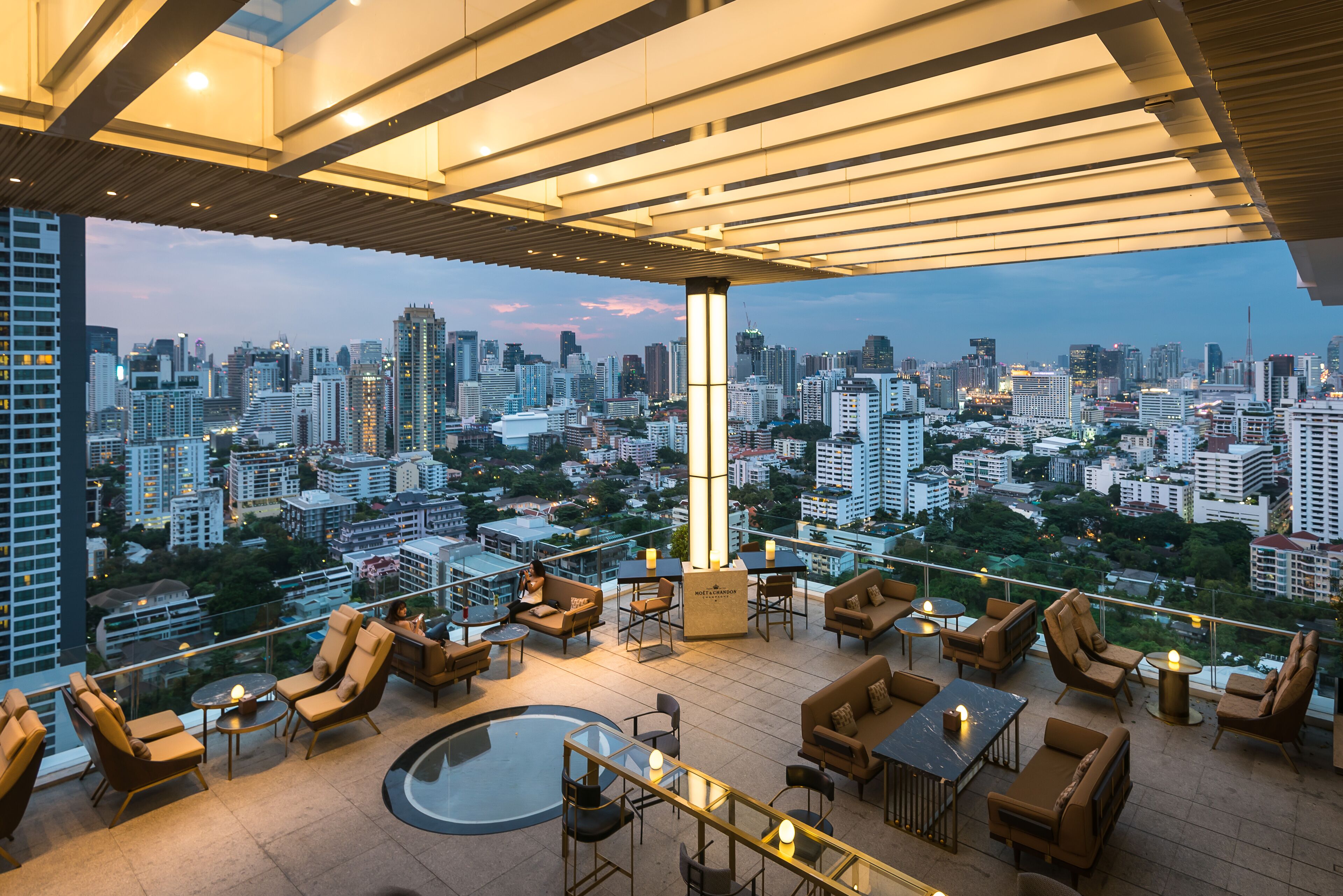 Stylish rooftop cocktail bar at 137 Pillars Suites Bangkok offering panoramic views of the city skyline and a chic, open-air ambiance at sunset.