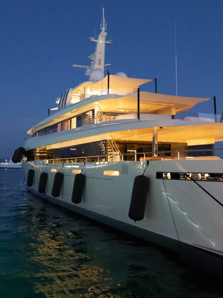 Luxury superyacht docked in Split, Croatia at twilight, glowing with warm onboard lighting against the deep blue evening sky—highlighting the city’s upscale waterfront and glamorous maritime culture.