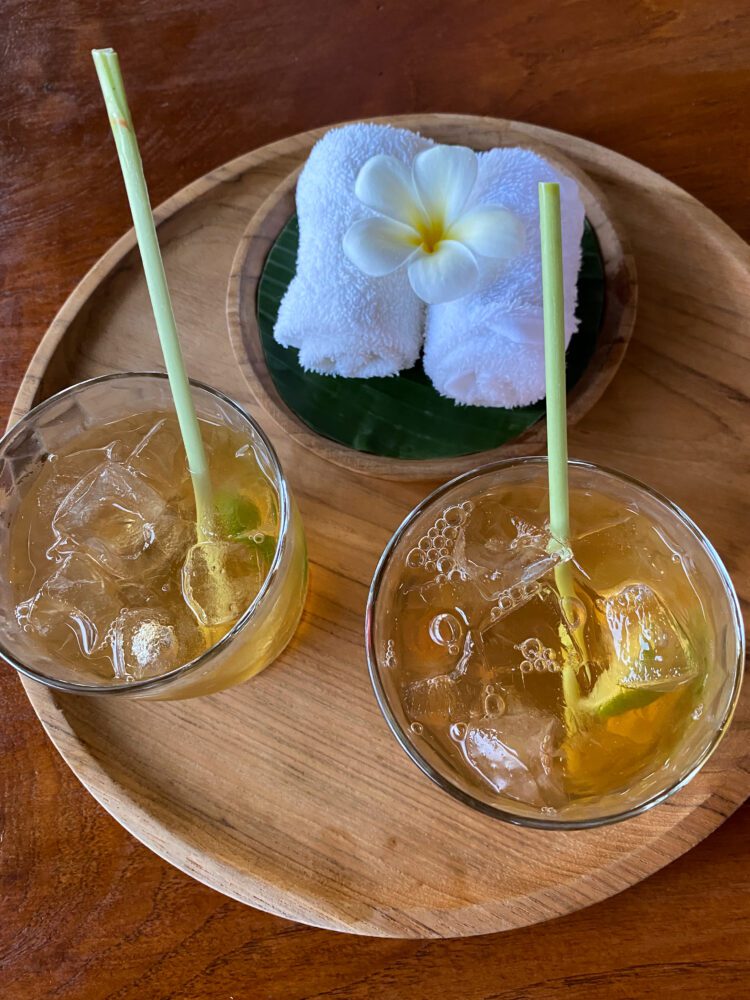 Welcome drink and cool towel with frangipani flower at Alila Ubud, a refreshing arrival ritual in Bali.