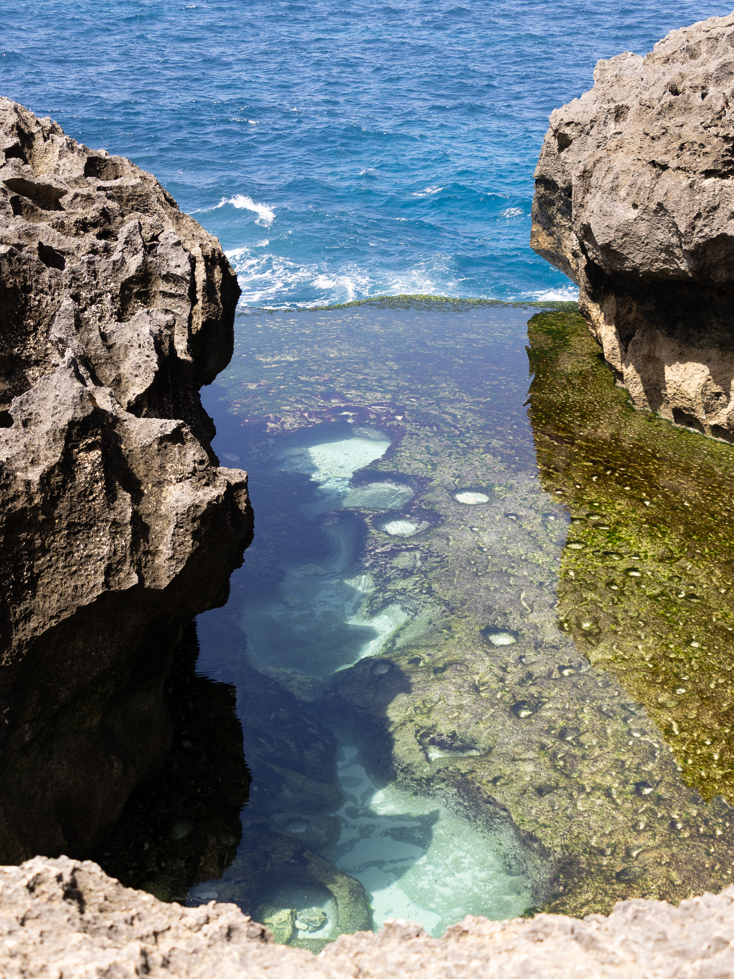 Natural infinity pool at Angel’s Billabong on Nusa Penida, where crystal-clear turquoise water flows between rugged limestone cliffs overlooking the open sea.