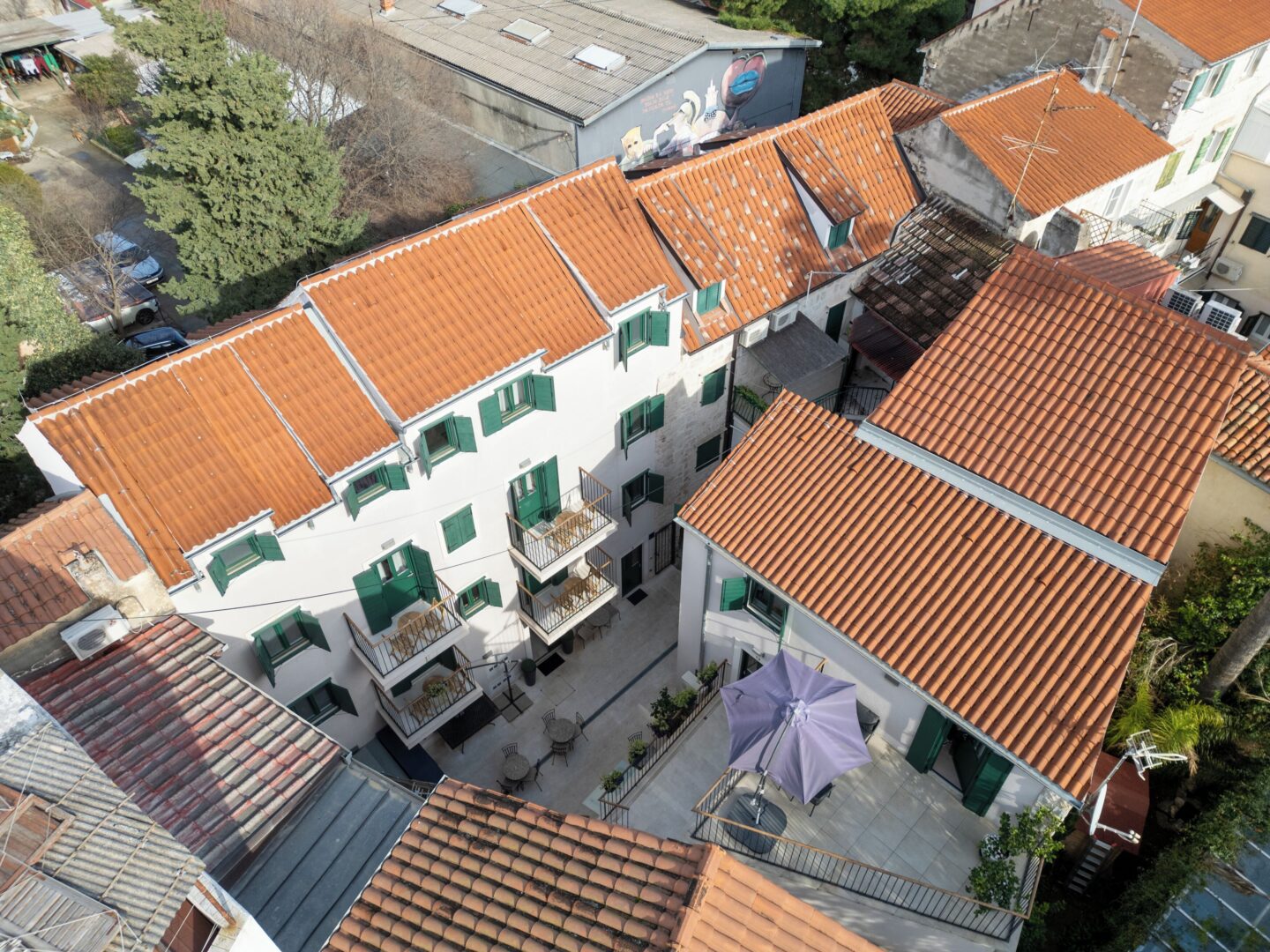 Charming hotel with green shutters in Split Croatia's Old Town, viewed from above alongside narrow lanes and leafy trees.