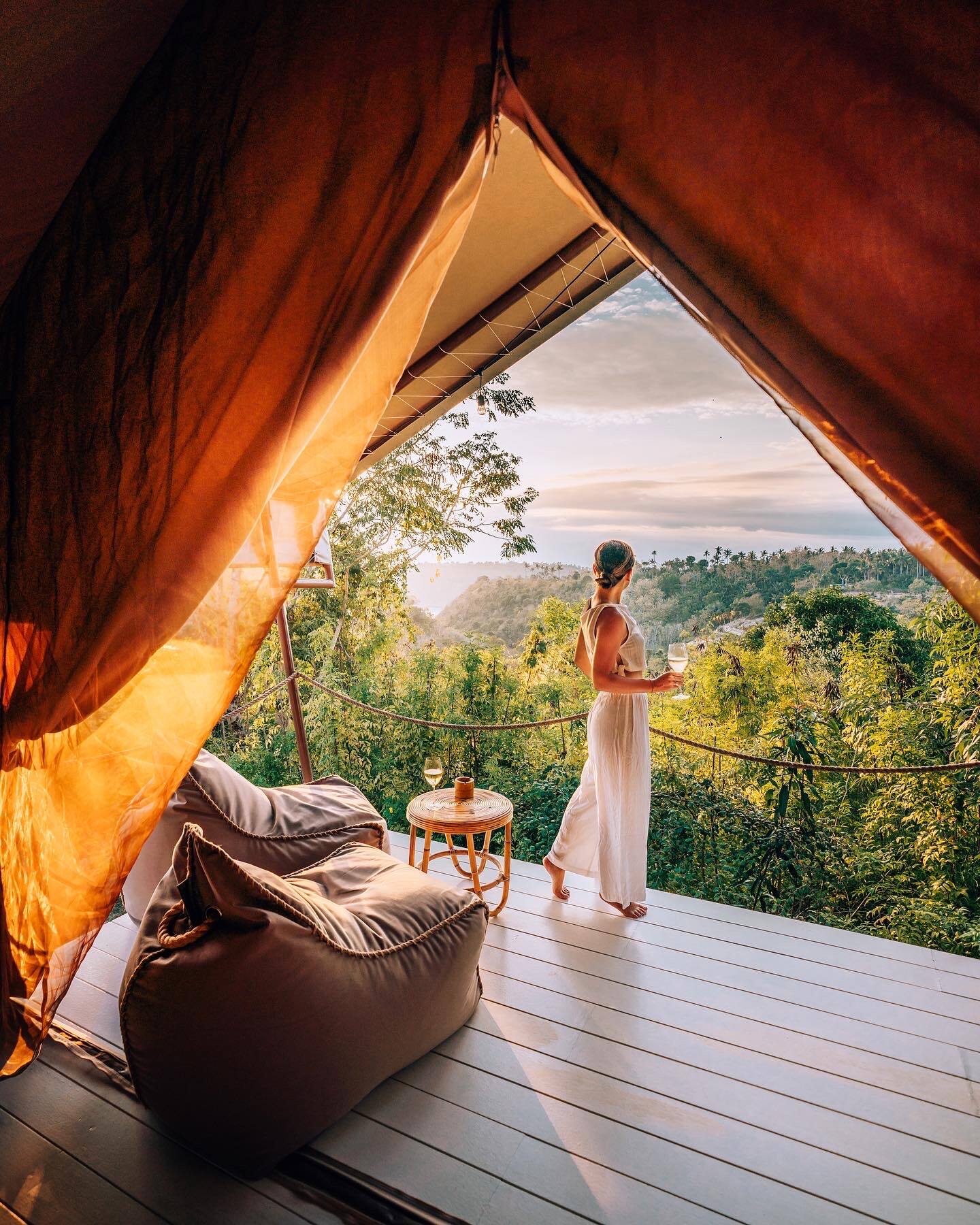 Woman enjoys a sunrise view over lush jungle from a luxury glamping tent at Autentik Penida.