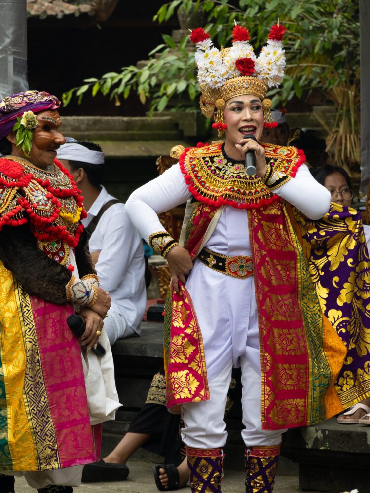 Balinese performers in vibrant traditional costumes singing during a cultural show at Batukaru Temple.