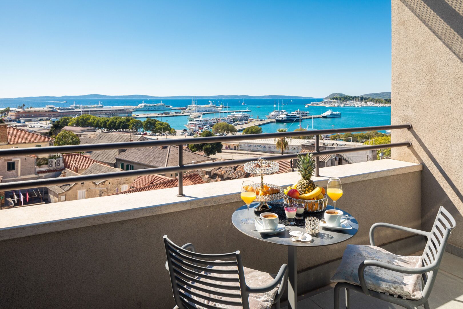 Breakfast table on a private balcony in one of the mid-range hotels in Split Croatia. The table is overlooking Split’s harbor and marina, with ferries and yachts dotting the Adriatic Sea.