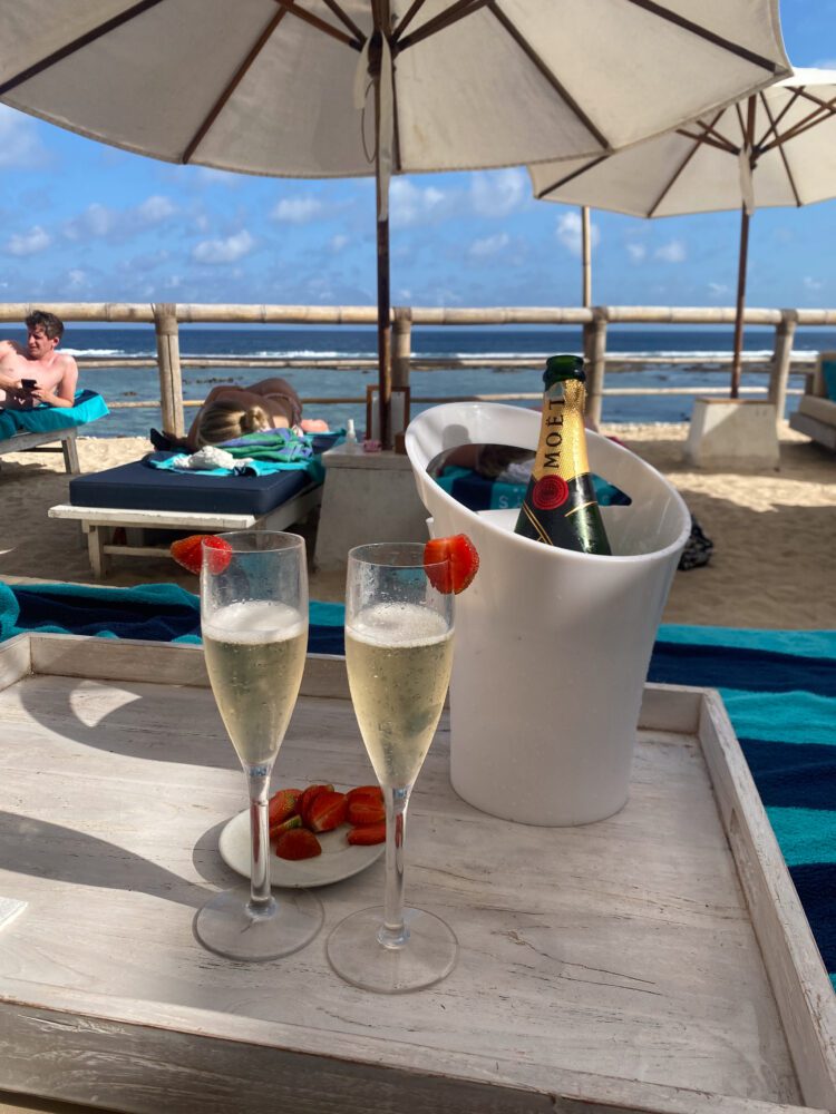 Chilled Moët & Chandon champagne with strawberries served under beach umbrellas at Sundays Beach Club, overlooking the waves of Uluwatu.