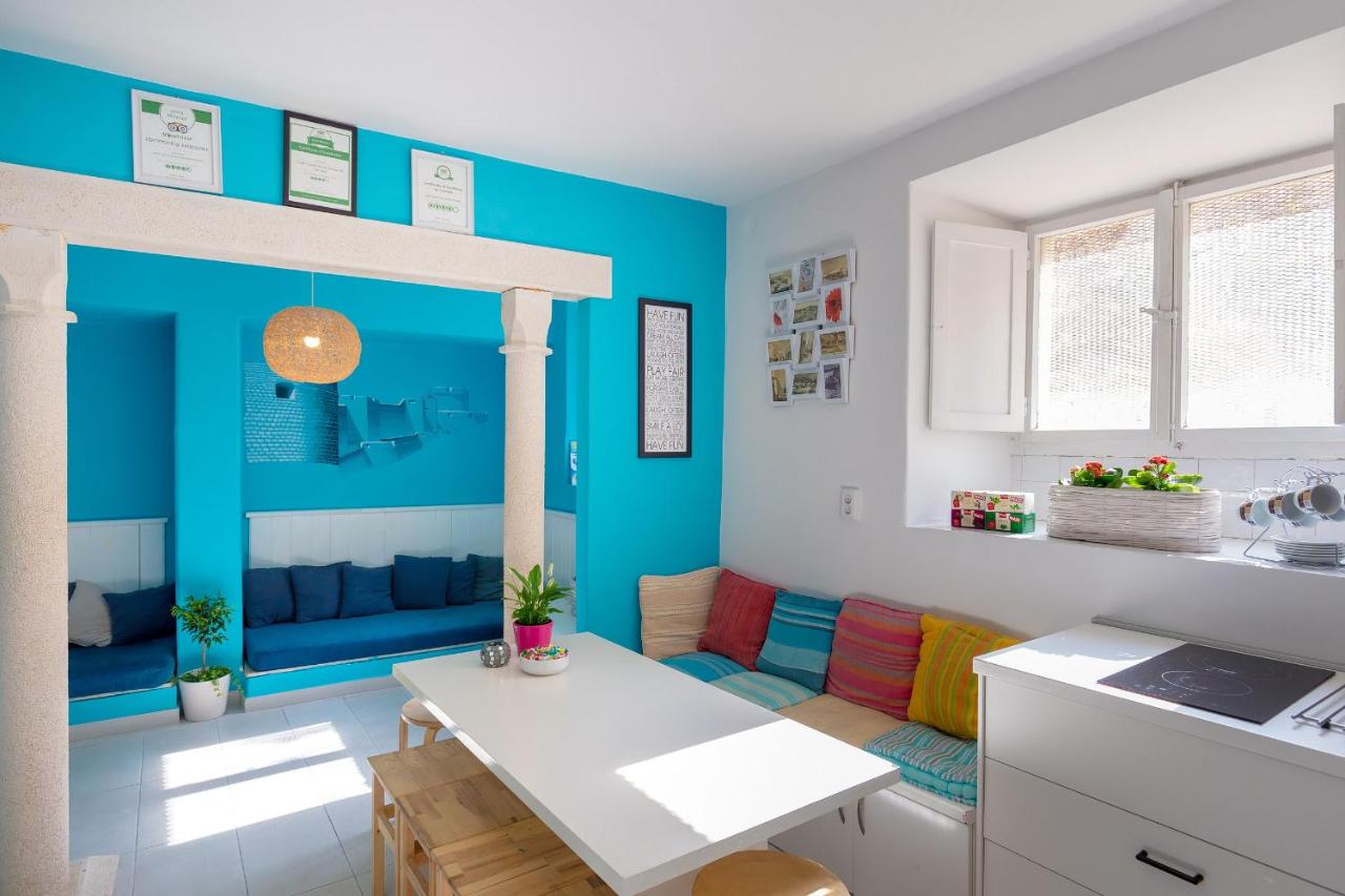 Bright and colorful common area at City Walls Hostel Dubrovnik featuring cheerful turquoise walls, cozy seating nooks, and a welcoming dining table by the window.