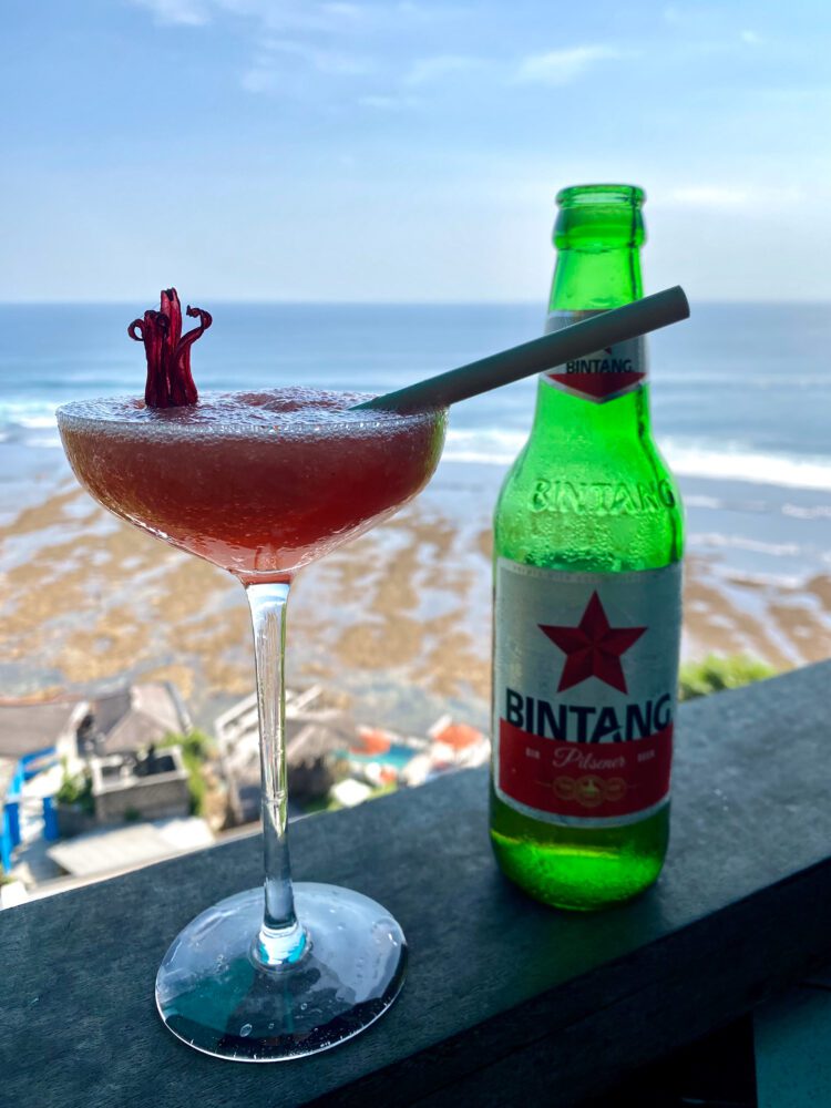 Refreshing hibiscus cocktail and cold Bintang beer at Single Fin Uluwatu, enjoyed with sweeping views of the Indian Ocean and reef below.