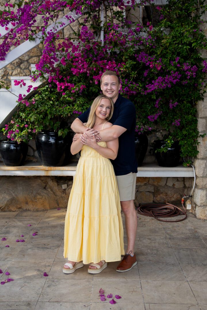 Smiling couple posing beneath vibrant bougainvillea at a romantic villa in Dubrovnik.