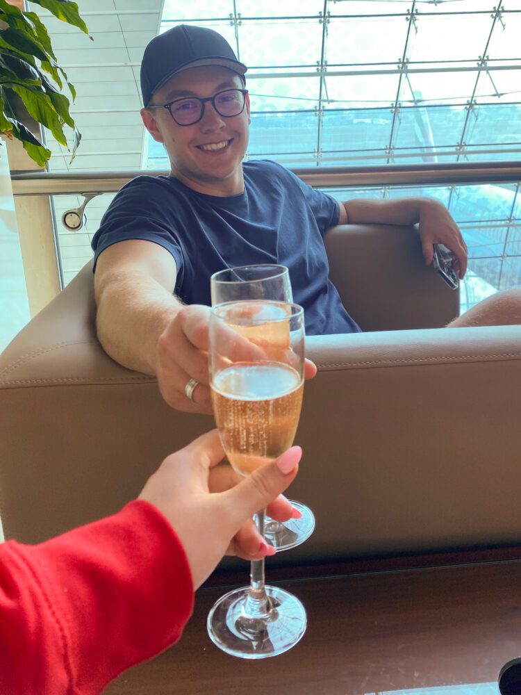 Couple clinking Moët & Chandon champagne glasses at an upscale airport lounge in Dubai before takeoff.