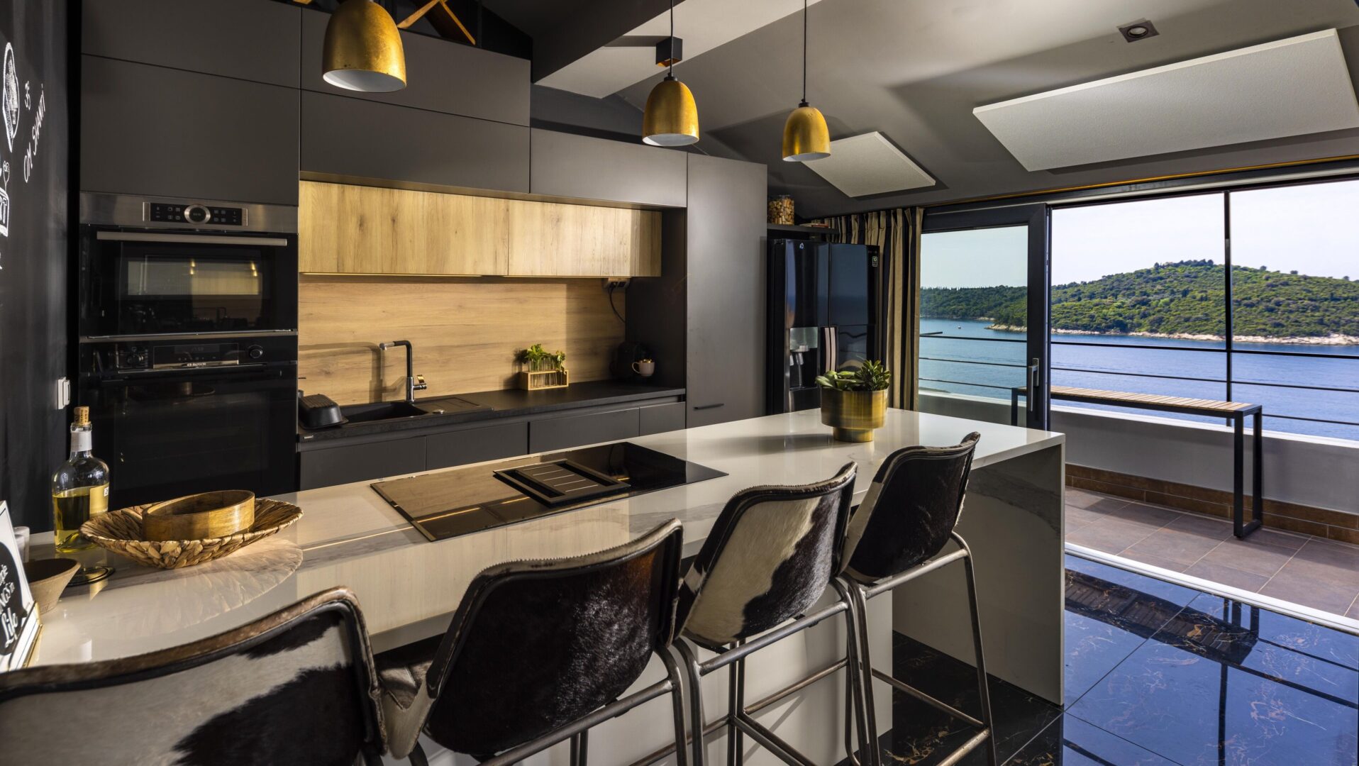 Sleek, modern kitchen at Dubrovnik Old Town Apartments with designer finishes, a balcony overlooking the Adriatic, and panoramic sea views through floor-to-ceiling glass doors.