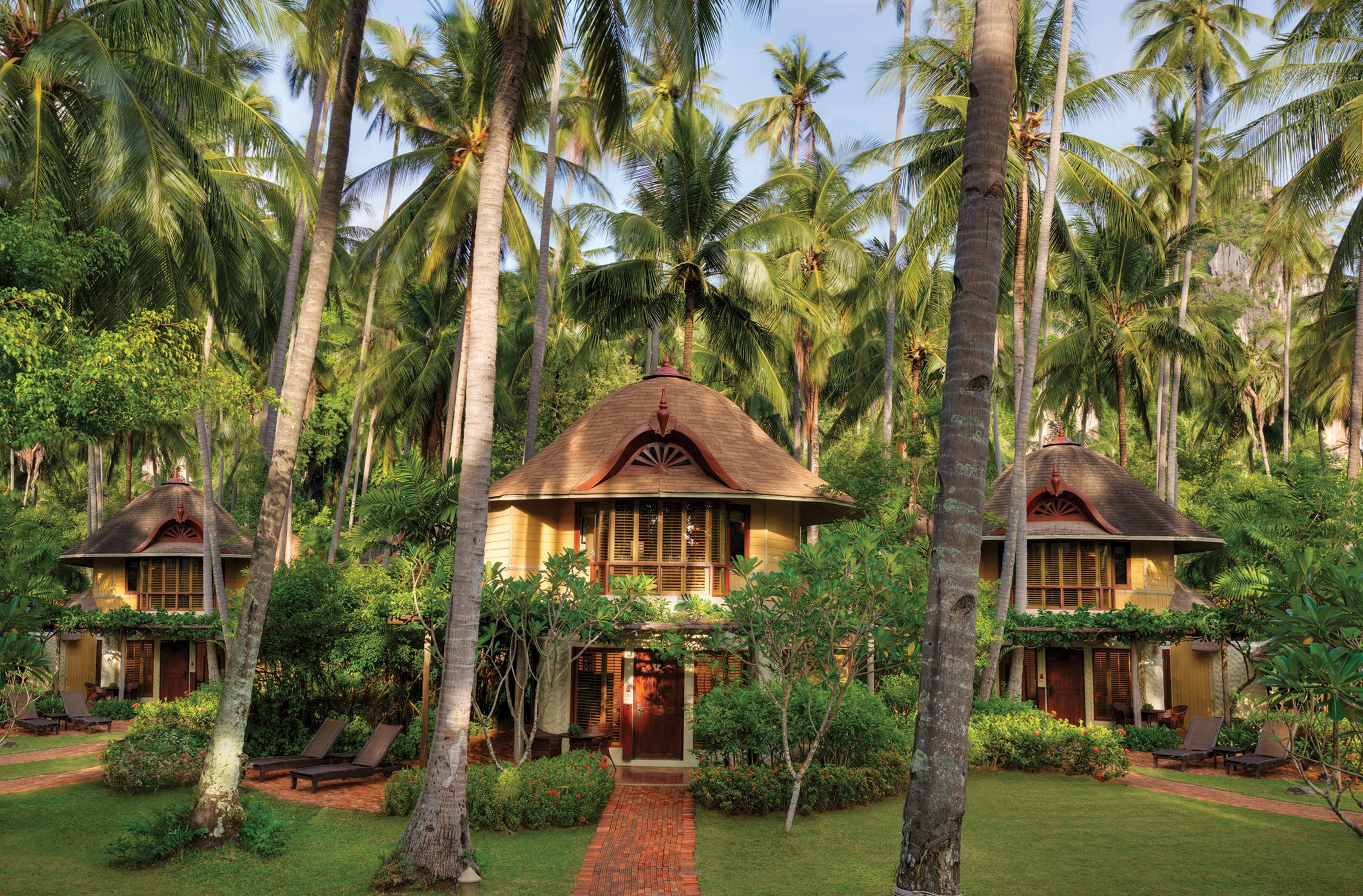 Tropical garden villas at Rayavadee Resort nestled among soaring palm trees and lush greenery, offering a secluded and serene escape on Thailand’s Railay Peninsula.