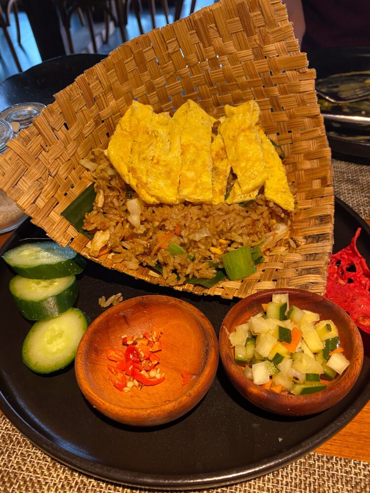 Traditional Indonesian fried rice served in a woven cone at Asri Dining in Sidemen, with egg strips, sambal, cucumber, and vegetable pickles.