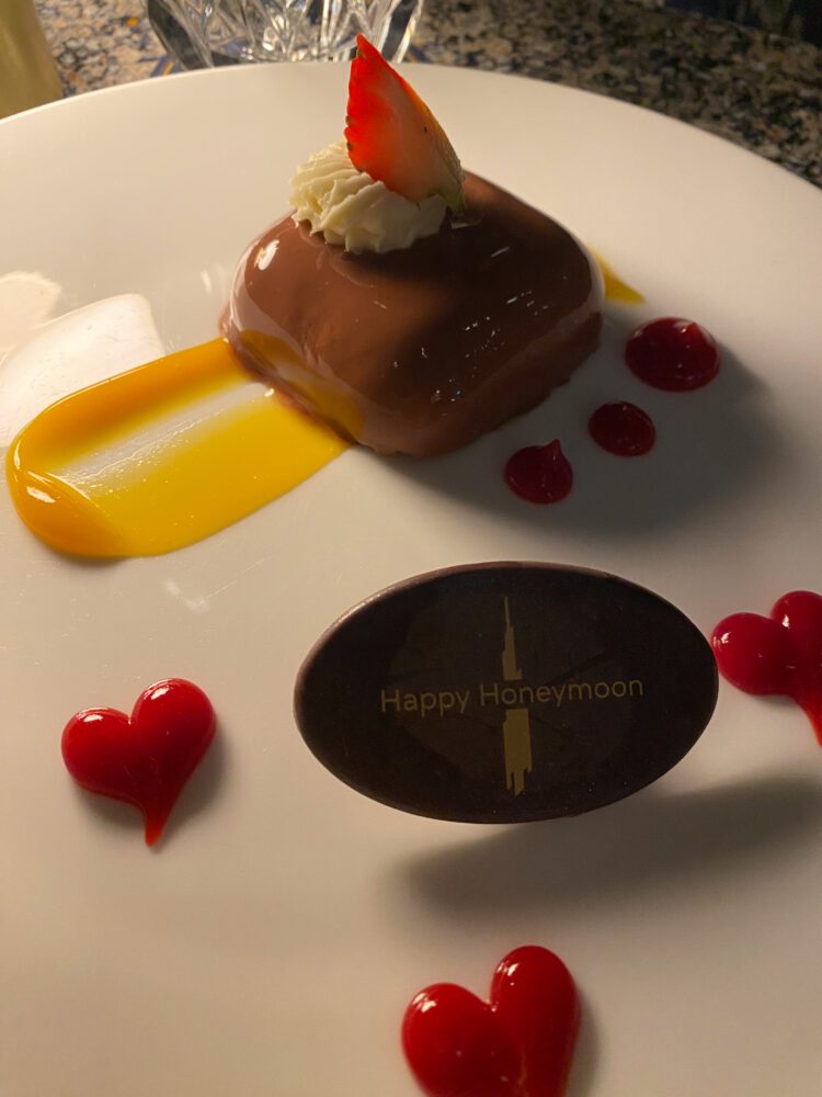 Elegant honeymoon dessert with mango sauce, chocolate plaque, and heart decorations served at Atmosphere Lounge in the Burj Khalifa.