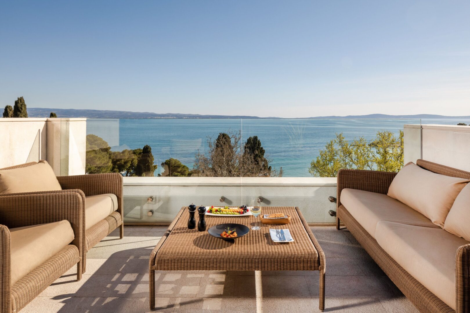 Spacious hotel terrace with wicker lounge seating and panoramic sea views, ideal for alfresco dining or relaxing above the Adriatic in Split, Croatia.