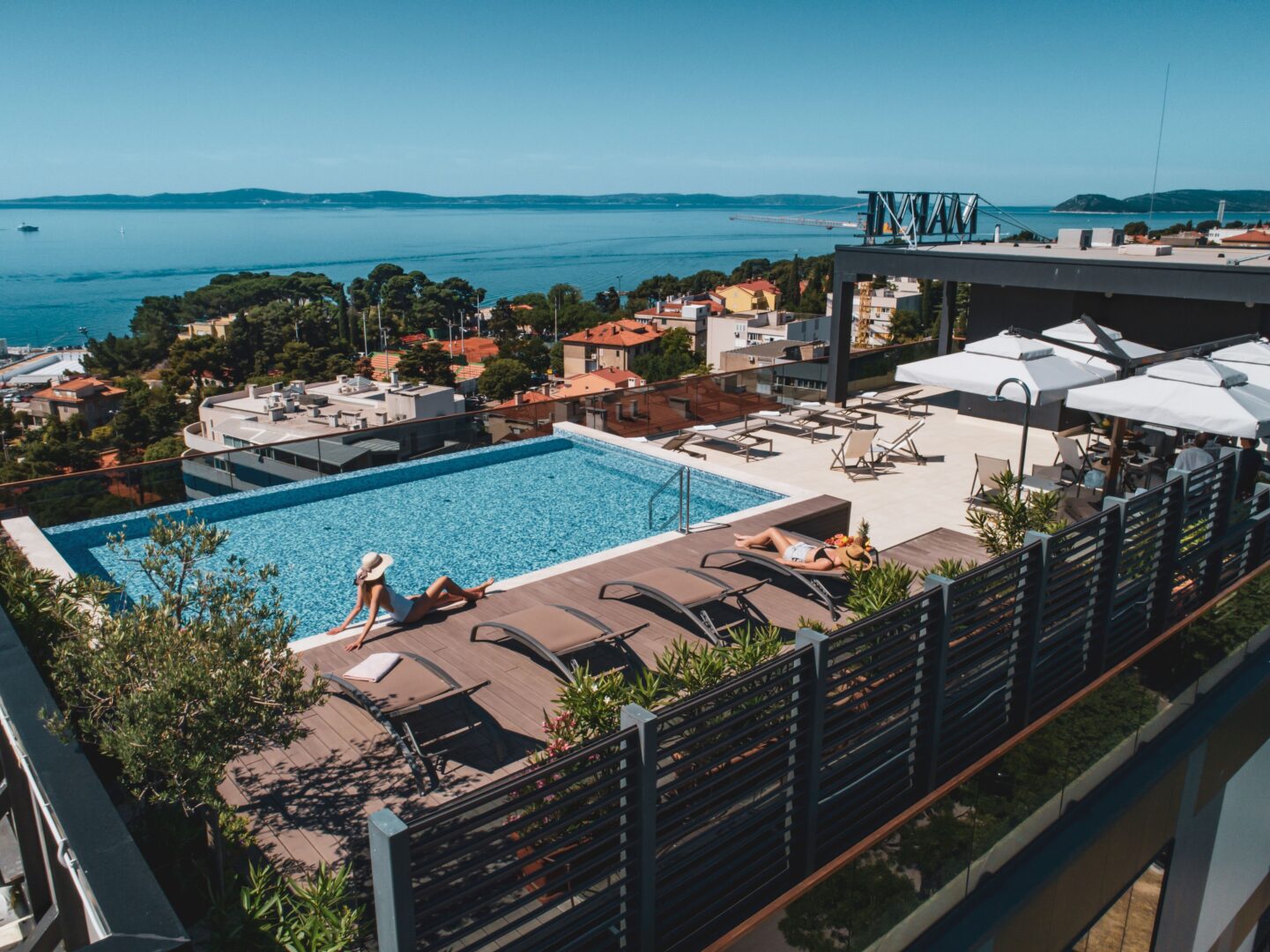 Modern hotel rooftop pool with sun loungers and sweeping views of Split Croatia's coastline and surrounding islands.