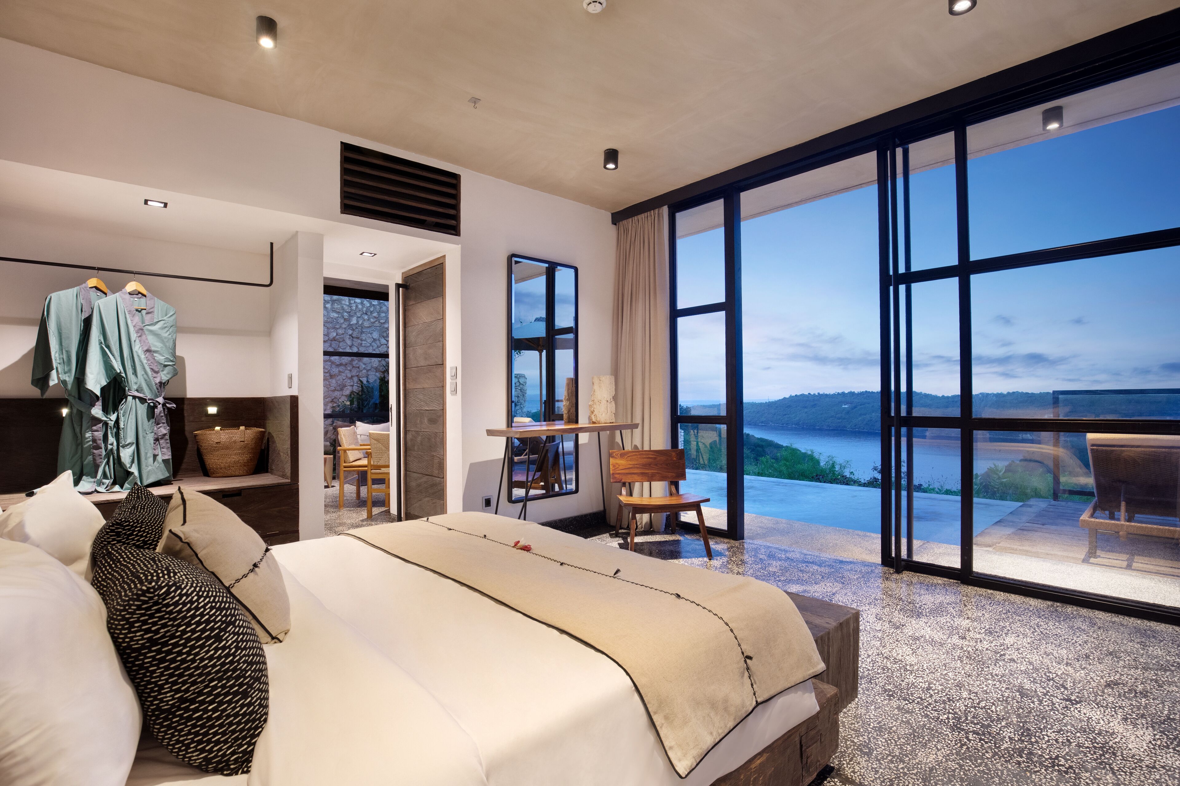 Modern luxury suite at Maua Nusa Penida featuring a minimalist design, spacious layout, and floor-to-ceiling windows overlooking the ocean and private plunge pool.