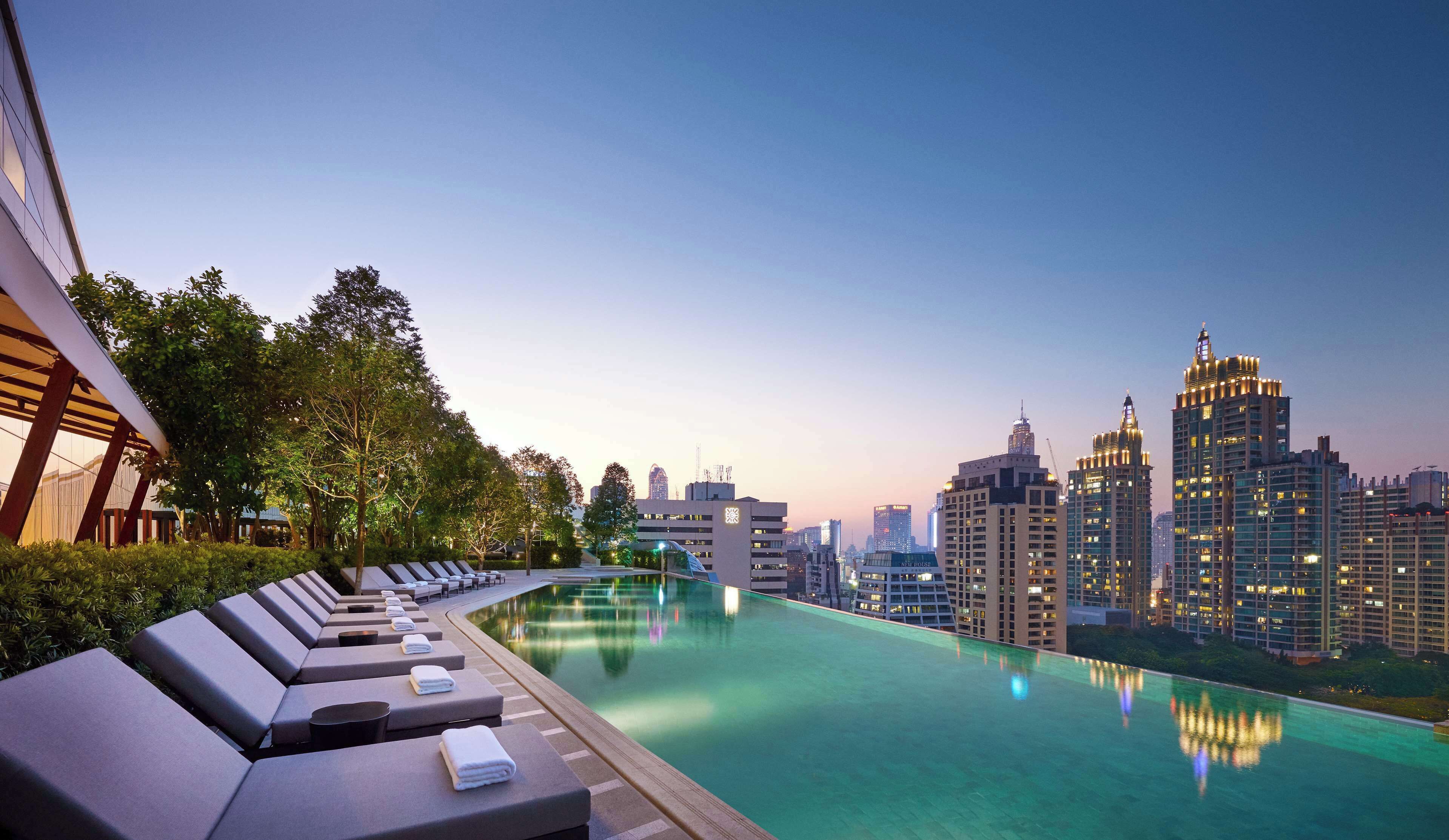 Rooftop infinity pool at Park Hyatt Bangkok with sleek loungers and panoramic views of the city skyline glowing at twilight.