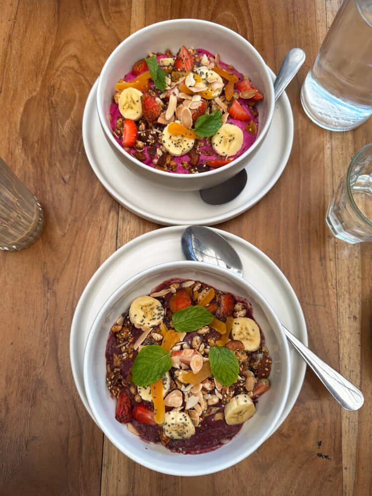 Colorful dragon fruit and acai smoothie bowls topped with fresh fruit and granola at Suka Espresso in Uluwatu.