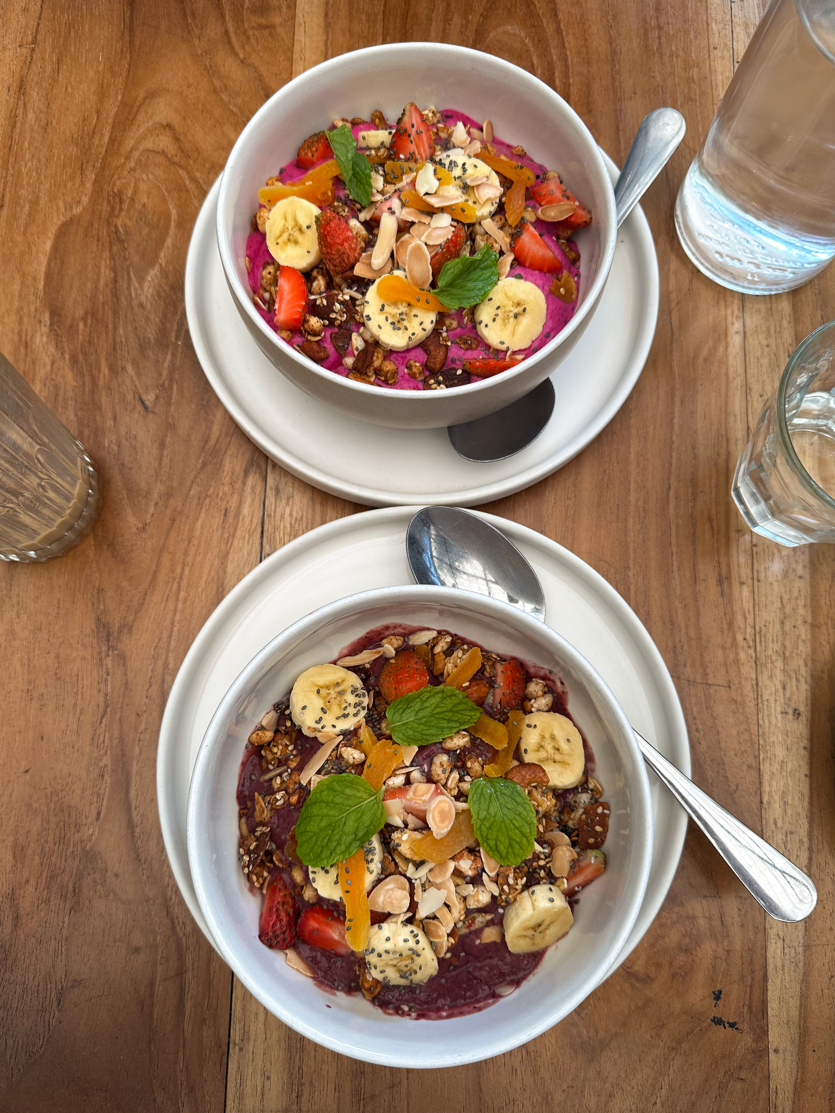 Colorful dragon fruit and acai smoothie bowls topped with fresh fruit and granola at Suka Espresso in Uluwatu.