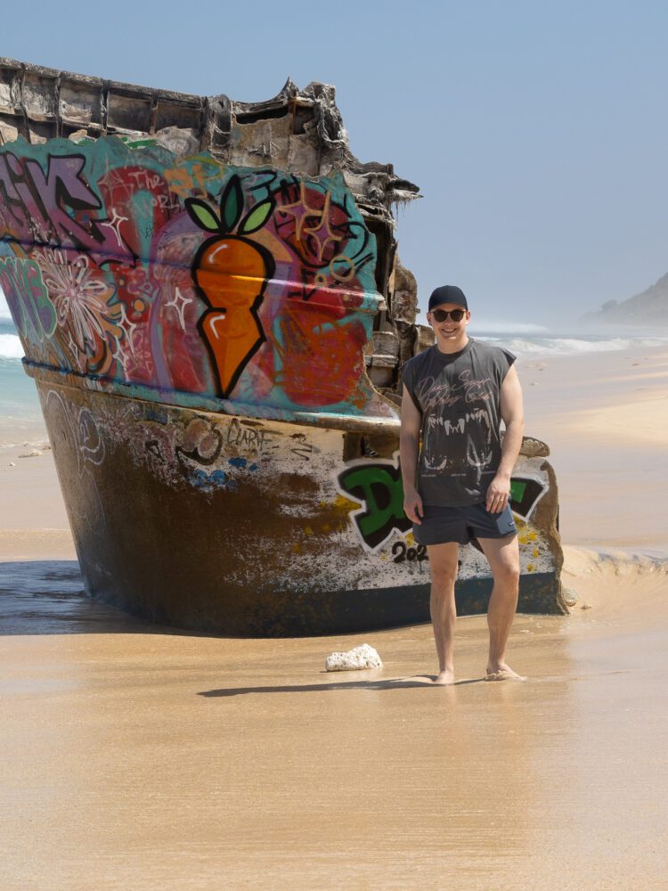 Graffiti-covered shipwreck on the sands of Nunggalan Beach in Uluwatu, creating a colorful contrast to the pristine shoreline.