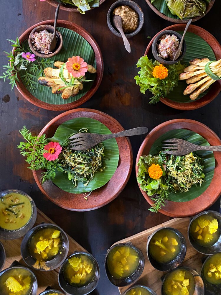 Beautifully plated traditional Balinese dishes featuring soup, satay, and salads during a Mai Organic cooking class.