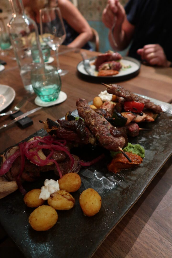 Platter of grilled meat skewers, roasted potatoes, and colorful sauces served at Taj Mahal restaurant in Dubrovnik.