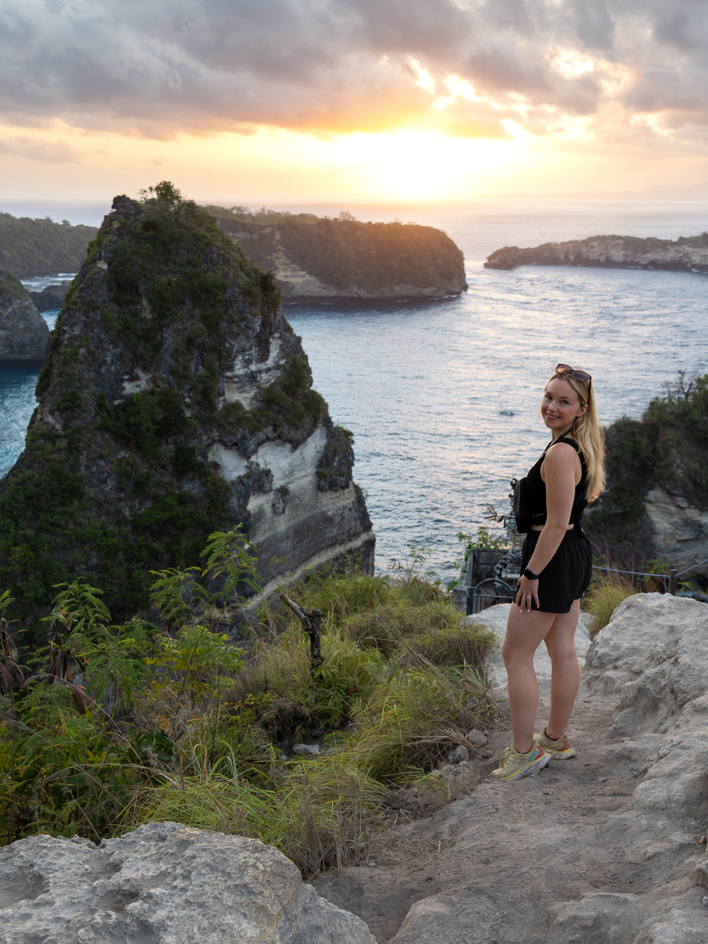 Woman admiring the sunrise from the Thousand Islands viewpoint in Nusa Penida, overlooking dramatic sea cliffs.