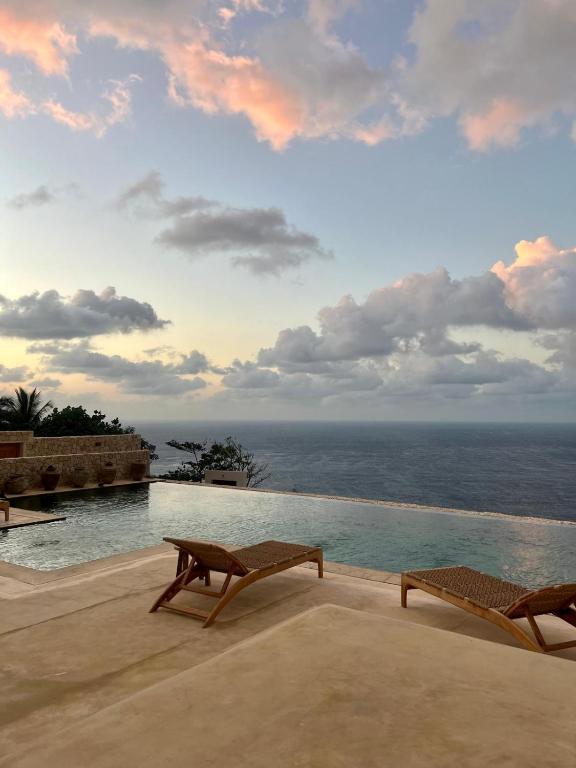 Sunset view over the Indian Ocean from Villa Sowilo’s cliffside infinity pool in Nusa Penida, framed by tropical skies and loungers.
