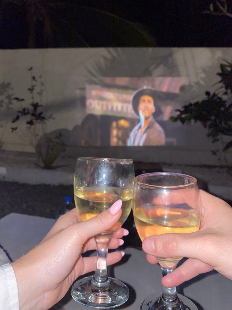 Toasting glasses of white wine during a cozy outdoor movie night under the stars in Nusa Penida.