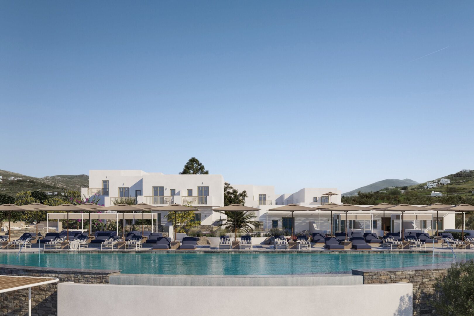 Outdoor infinity pool at Cosme Hotel Paros surrounded by loungers, parasols, and Cycladic-style buildings with hillside views.