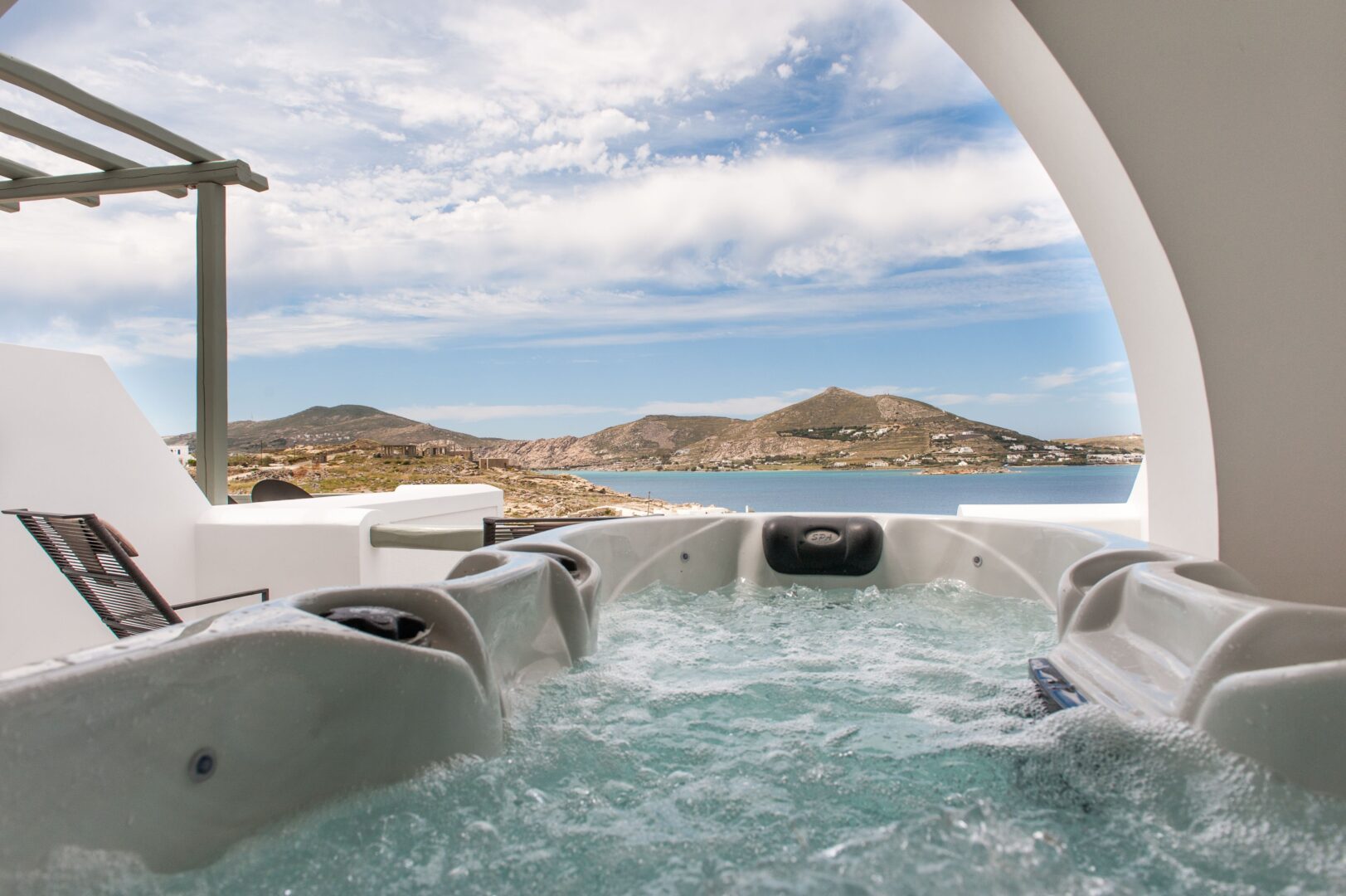 Private suite hot tub at Hotel Senia Paros overlooking the Aegean Sea and surrounding hills under a bright sky.