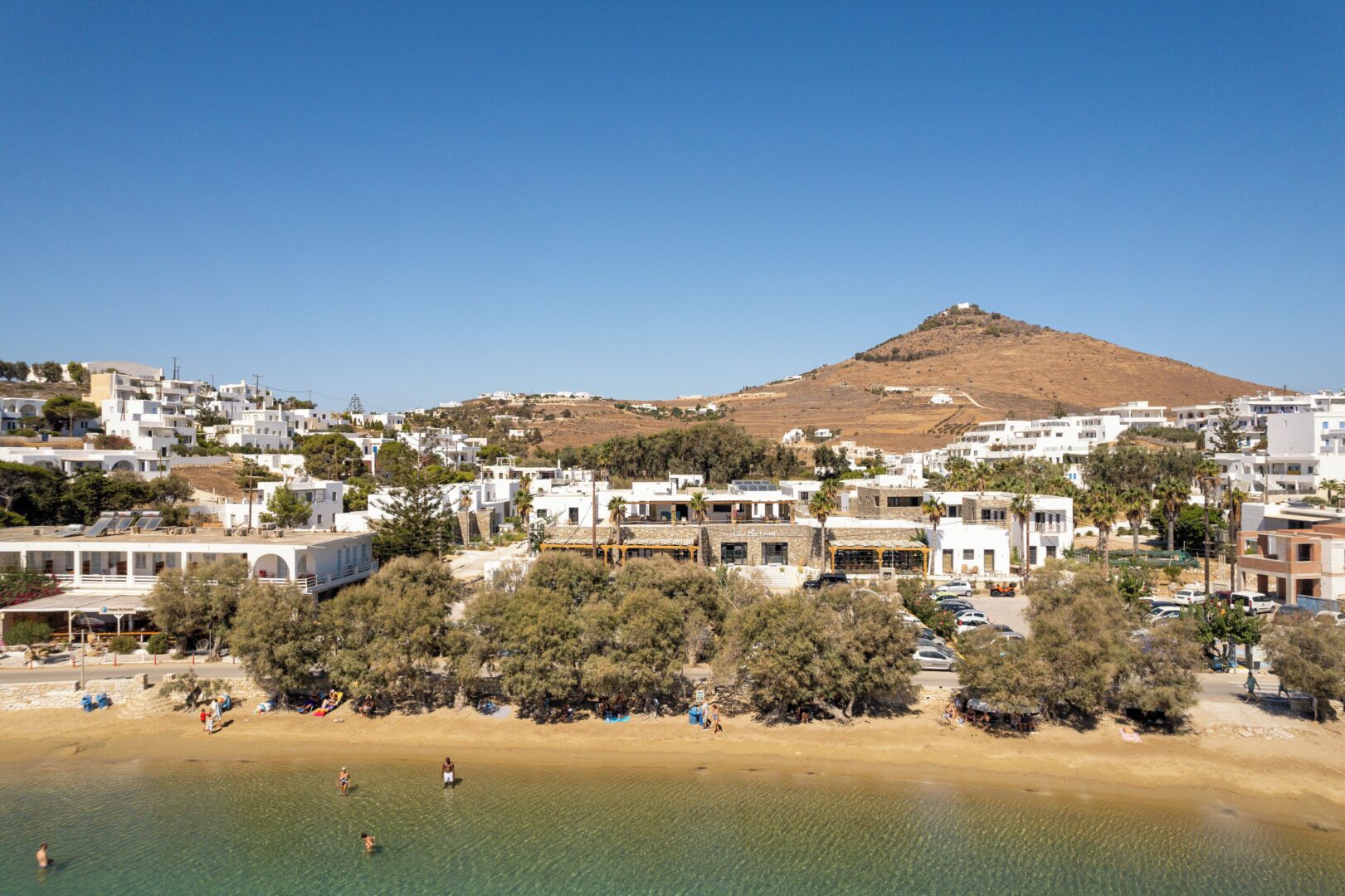 Scenic view of Piso Livadi Paros with beachfront tavernas, Cycladic buildings, and gentle waves.