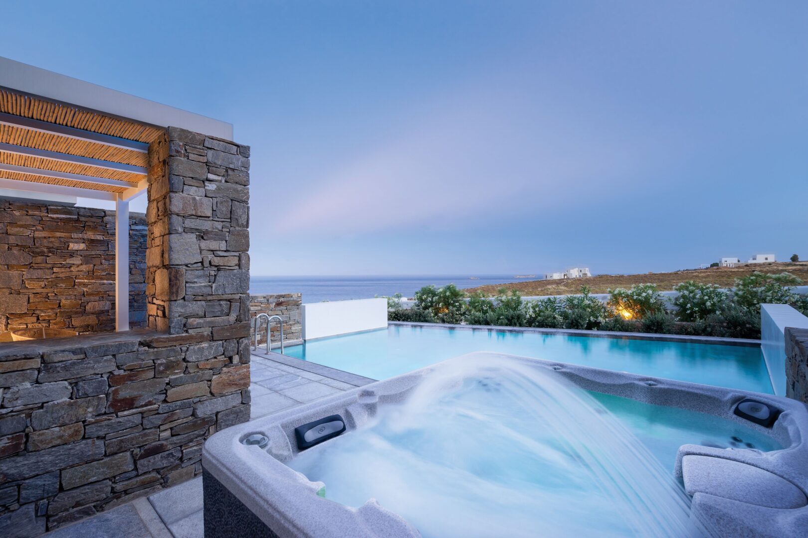 Honeymoon suite at Summer Senses Luxury Resort Paros featuring an outdoor jacuzzi and pool with sea views at sunset.