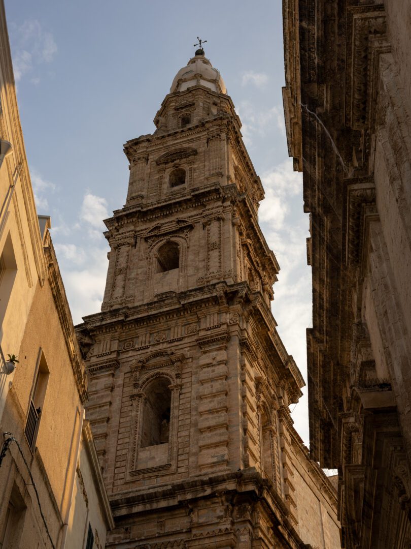 Towering bell tower of Basilica Cattedrale Maria Santissima della Madia in Monopoli glowing in golden hour light.