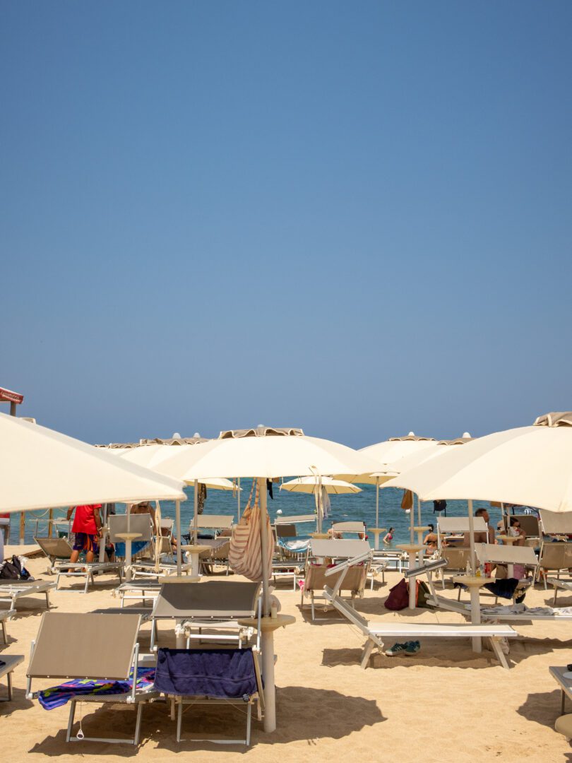 Sun loungers and umbrellas set up on the golden sand at Lido Cala Paradiso beach club in Monopoli, Puglia.