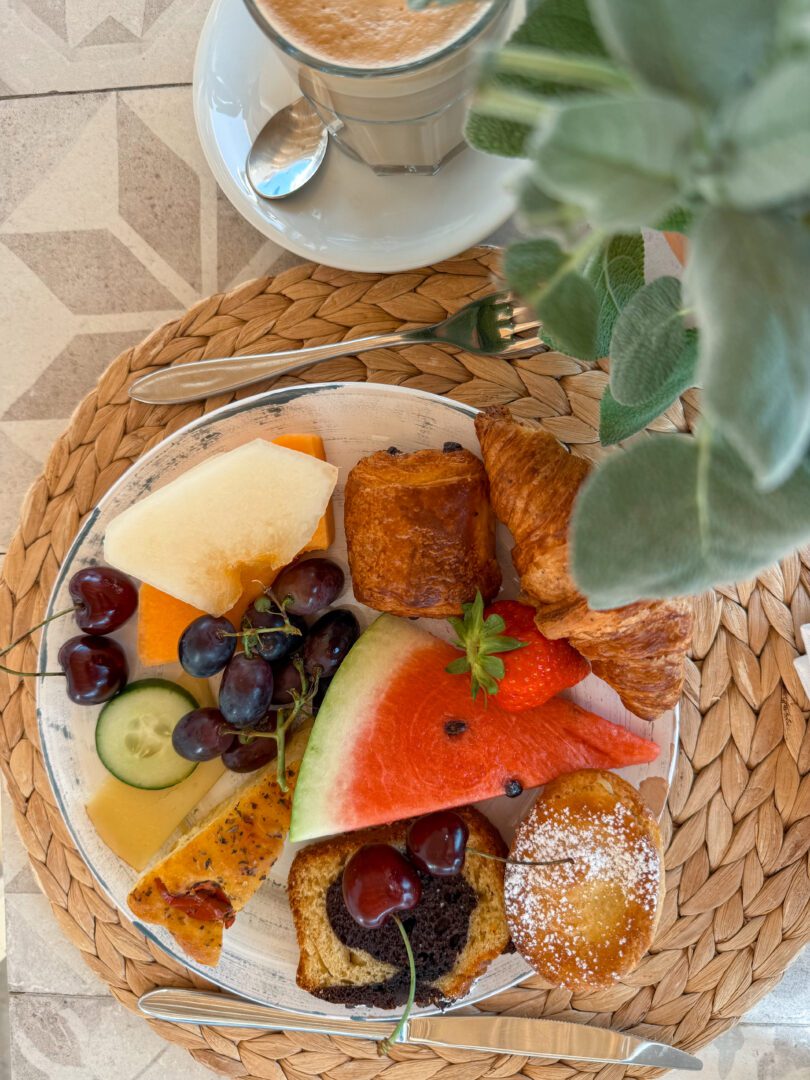 A vibrant plate of fresh fruit, pastries, and focaccia served with a cappuccino at Masseria Borgo Ritella in Puglia.