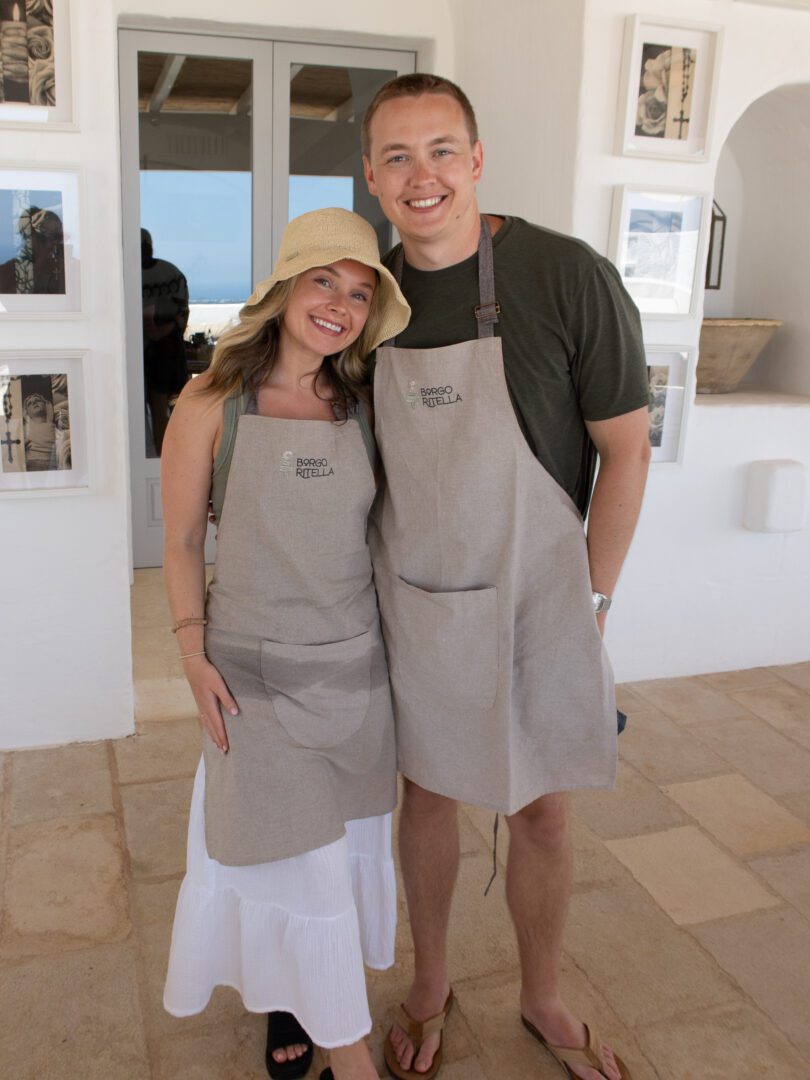 Couple wearing aprons at a cooking class at Masseria Borgo Ritella in Puglia, Italy.