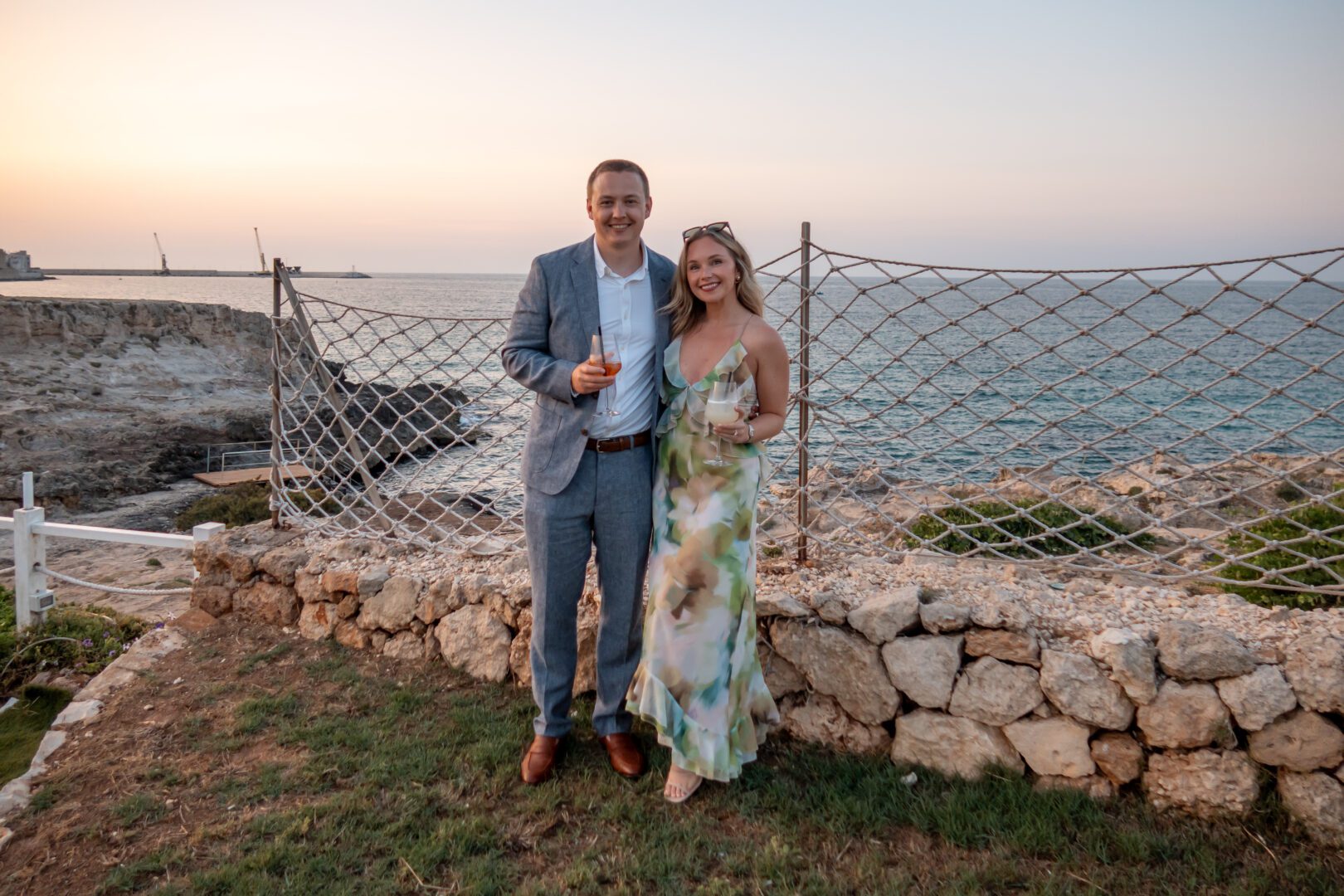 A well-dressed couple enjoys cocktails at golden hour overlooking the Adriatic Sea at La Perla Nera beach club.