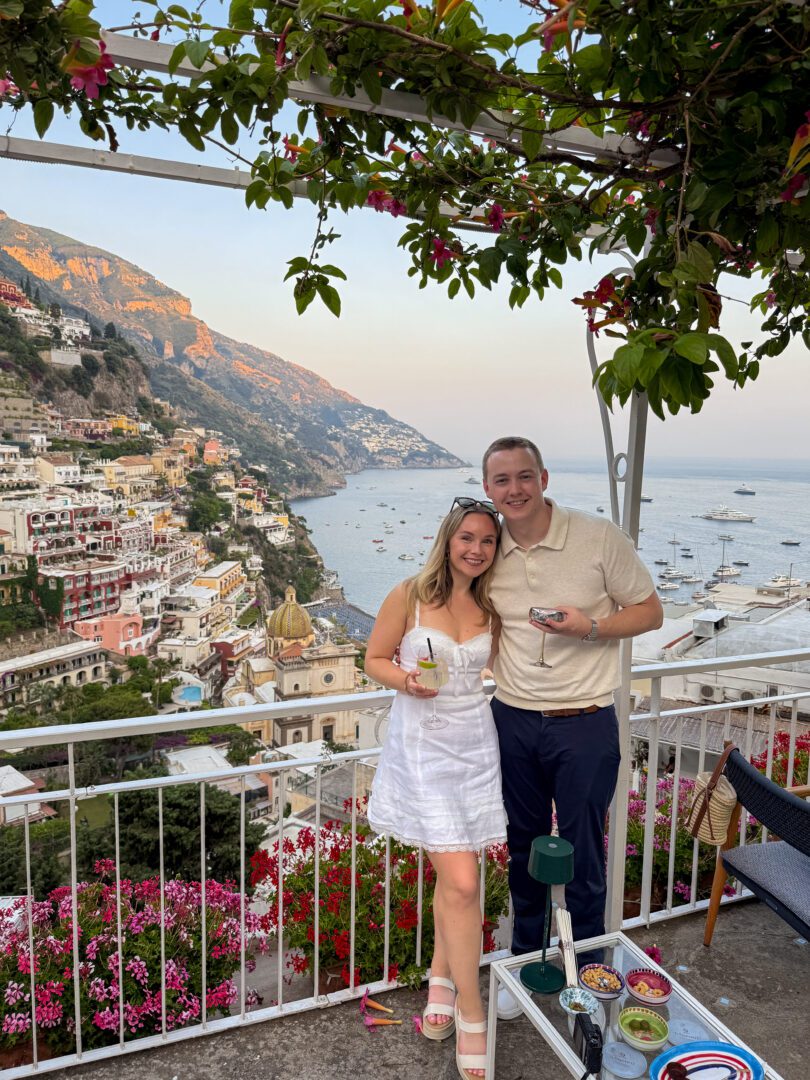 Couple enjoying cocktails at Il Tridente Bar in Positano, with sweeping views of the Amalfi Coast at golden hour.