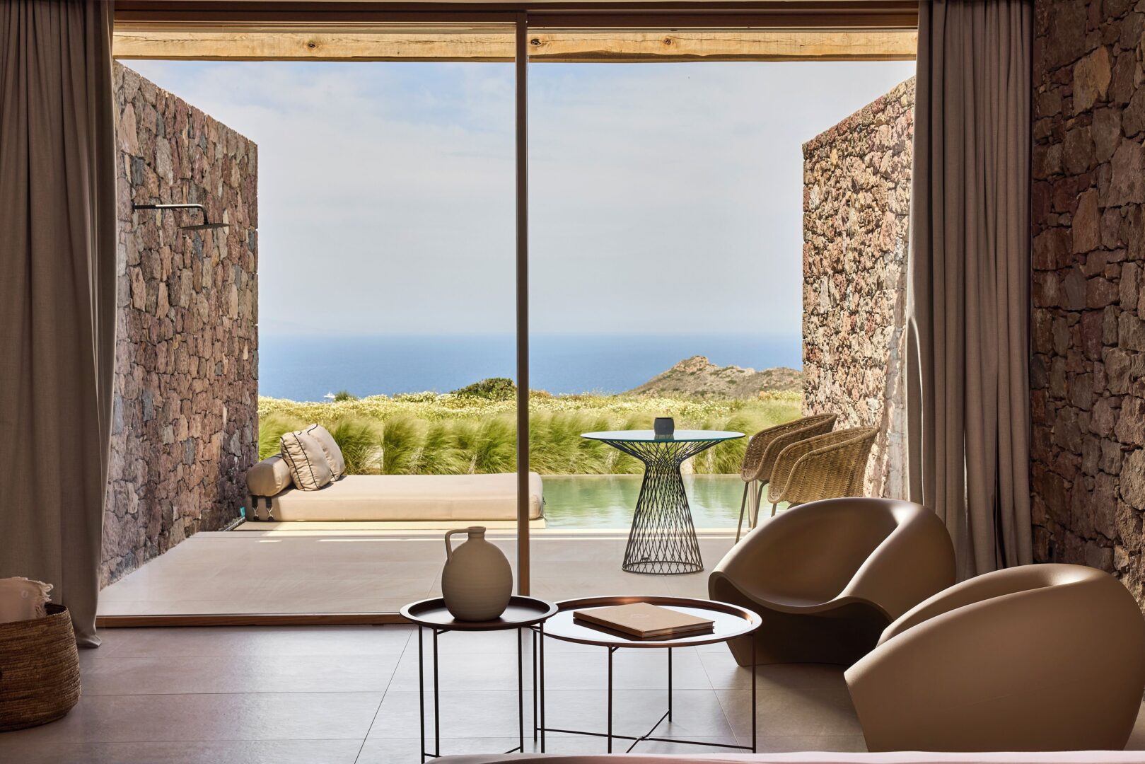 Luxurious suite at D3 Milos Hotel with floor-to-ceiling glass doors, private pool, and uninterrupted views of the sea and wild landscape.