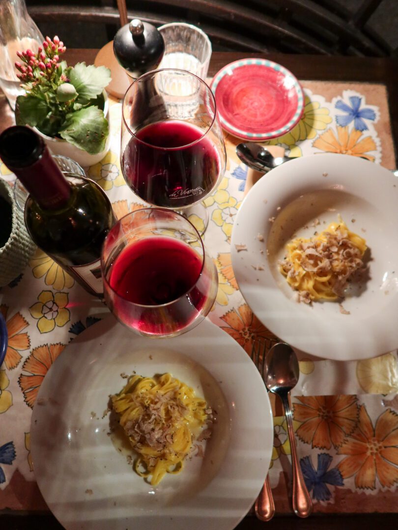 Overhead view of truffle tagliolini and red wine on a colorful tiled table at Da Vincenzo restaurant in Positano.