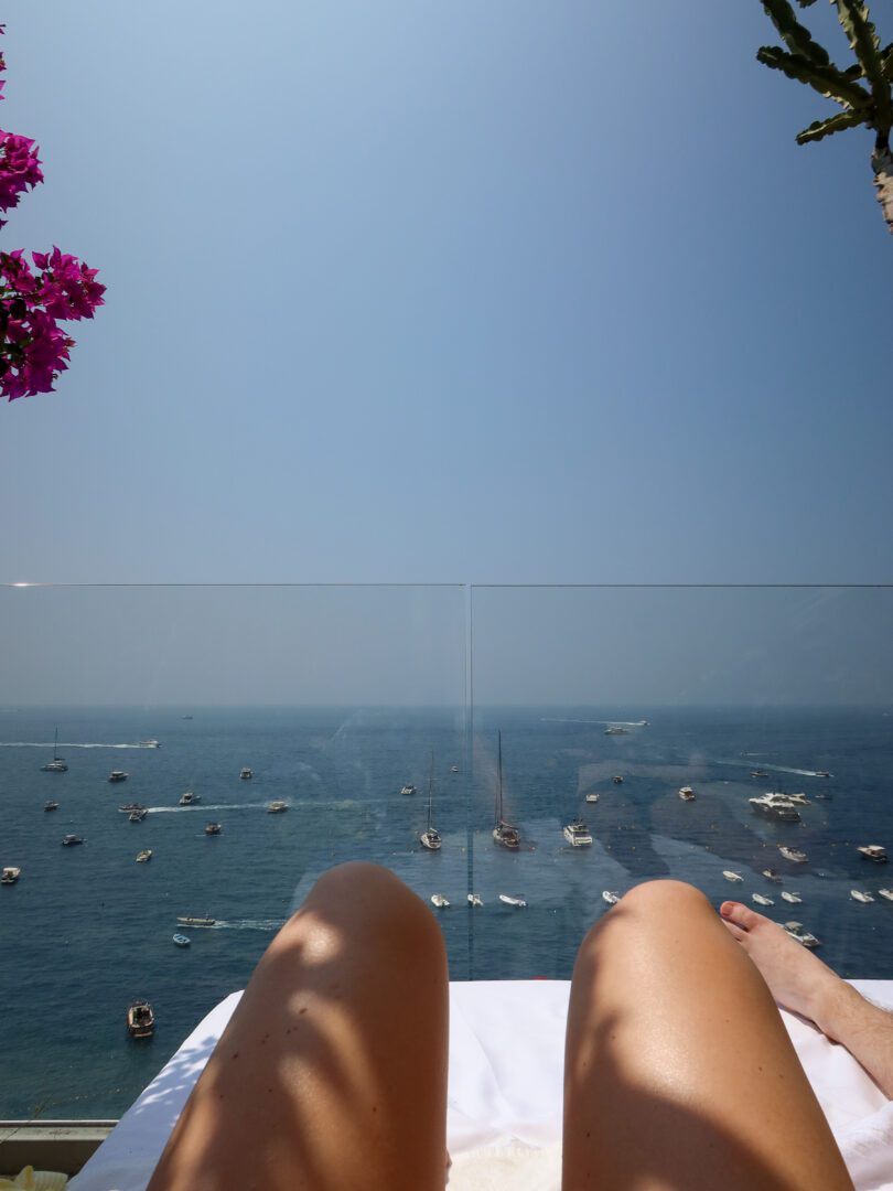 Lounging on a daybed overlooking the Tyrrhenian Sea from Hotel Marincanto in Positano, with boats dotting the deep blue water below.