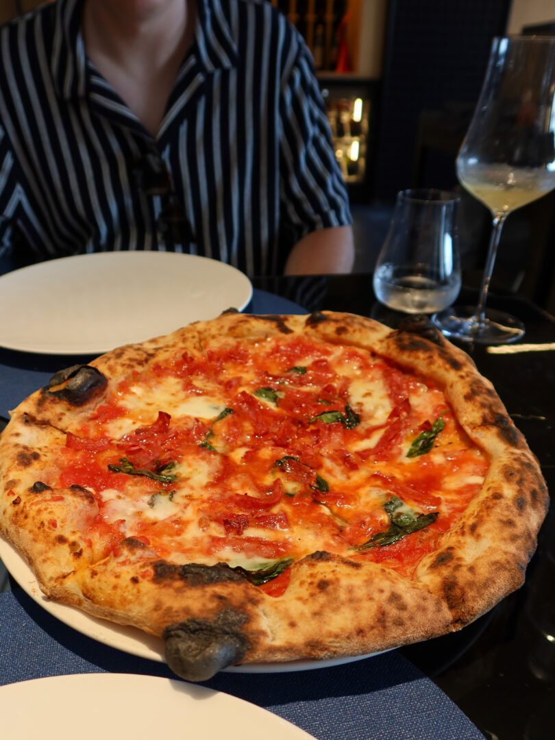 Close-up of a wood-fired Diavola pizza with spicy salami and basil at Ristorante Roc Pizza and Stead in Positano.