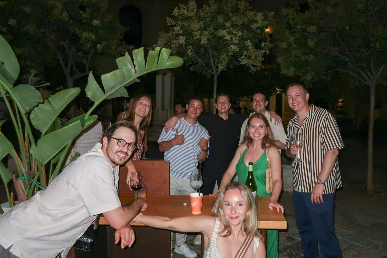Friends enjoying wine and cocktails in a lively courtyard bar in Monopoli, Italy on a summer evening.