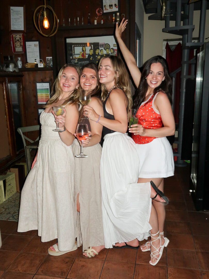 Four women celebrating with cocktails at Alchemico Bar e Cose in Monopoli, capturing the energy of Italian nightlife.
