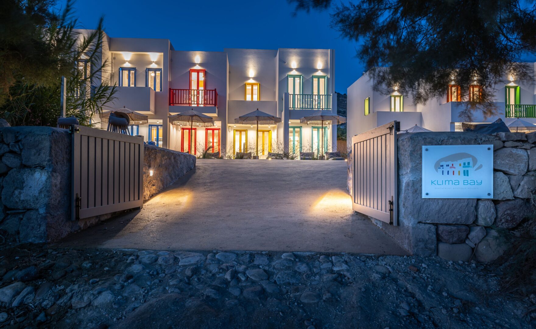 Colorful and modern Cycladic-style beachfront suites at Klima Bay Boutique Houses, warmly lit at night and just steps from the sea.