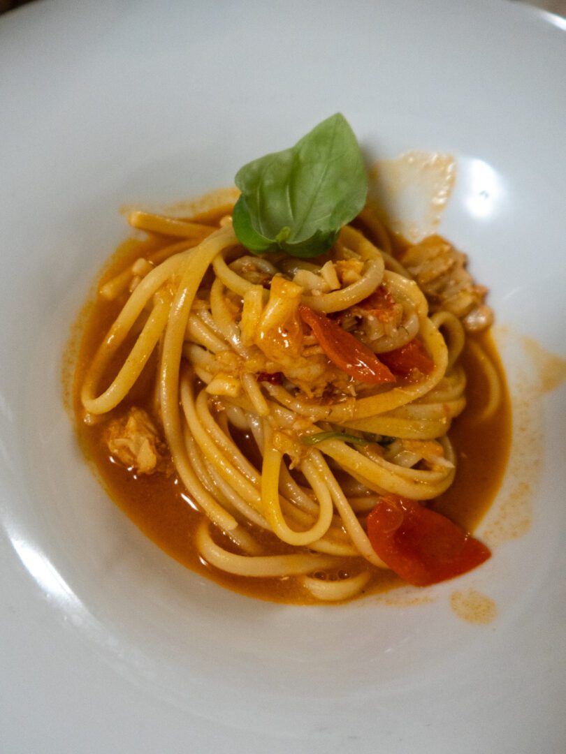 Plate of lobster pasta with cherry tomatoes and basil at Antica Posta, a seafood-focused restaurant in Monopoli.