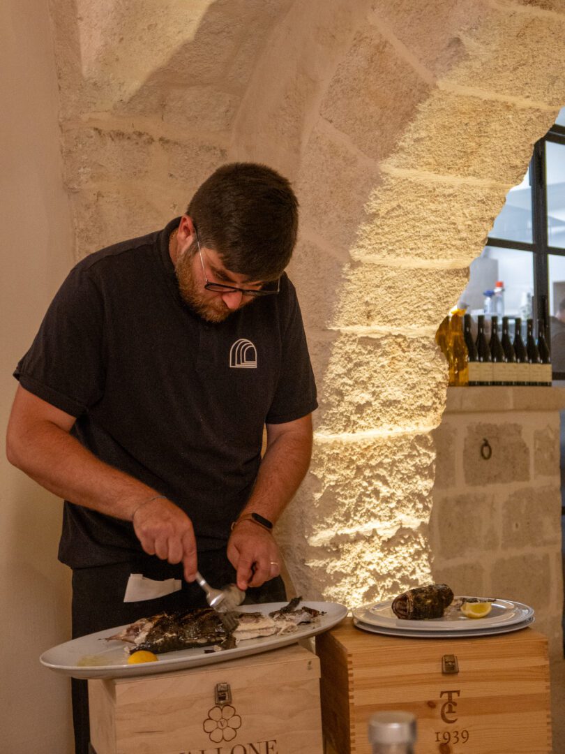 Server carving freshly grilled fish tableside at Antica Posta restaurant in Monopoli, known for its coastal cuisine.