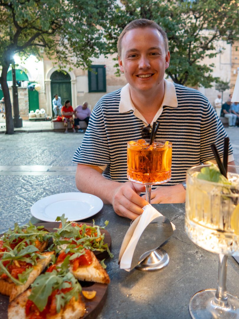 Man enjoying an Aperol spritz and bruschetta at an outdoor café in Matera, a charming town in Puglia, Italy.