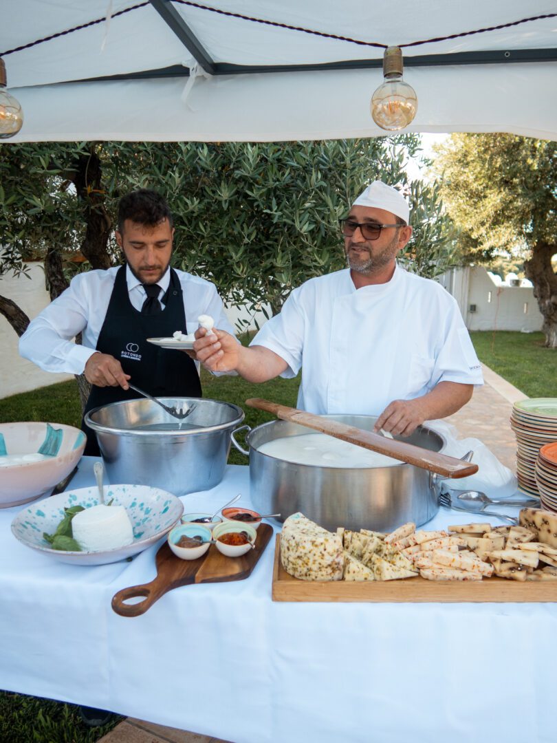Chef preparing fresh mozzarella at a wedding in Italy, with a rustic cheese and antipasti display.